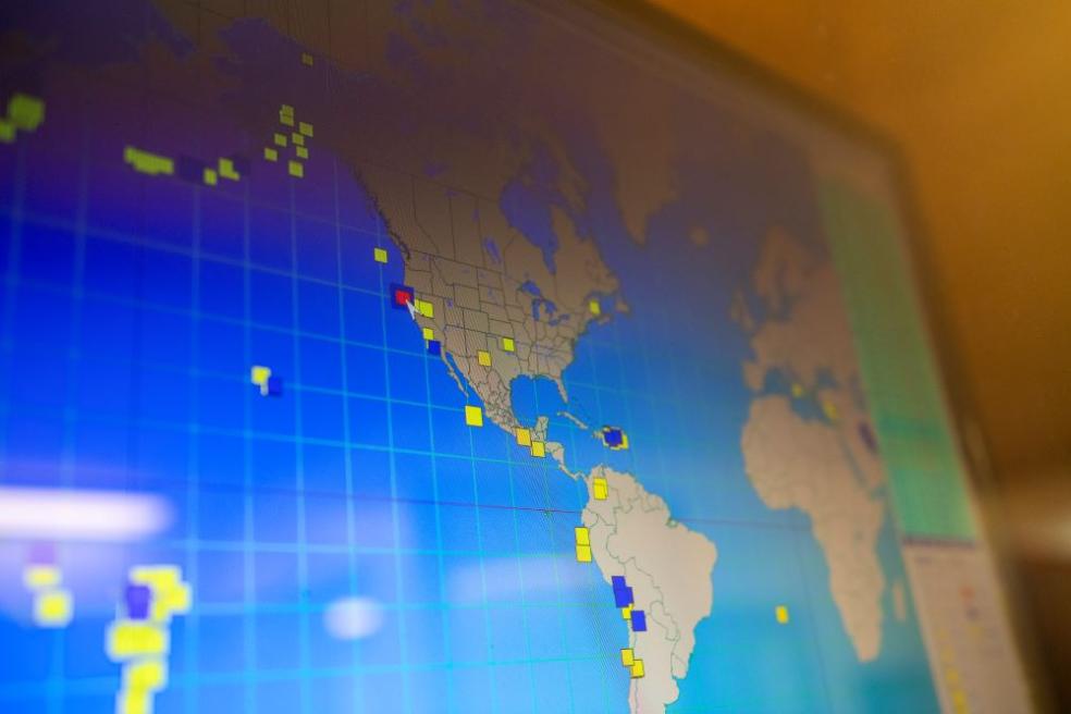 A photo of a map of North and South America filled with red and yellow dots indicating seismic activity.