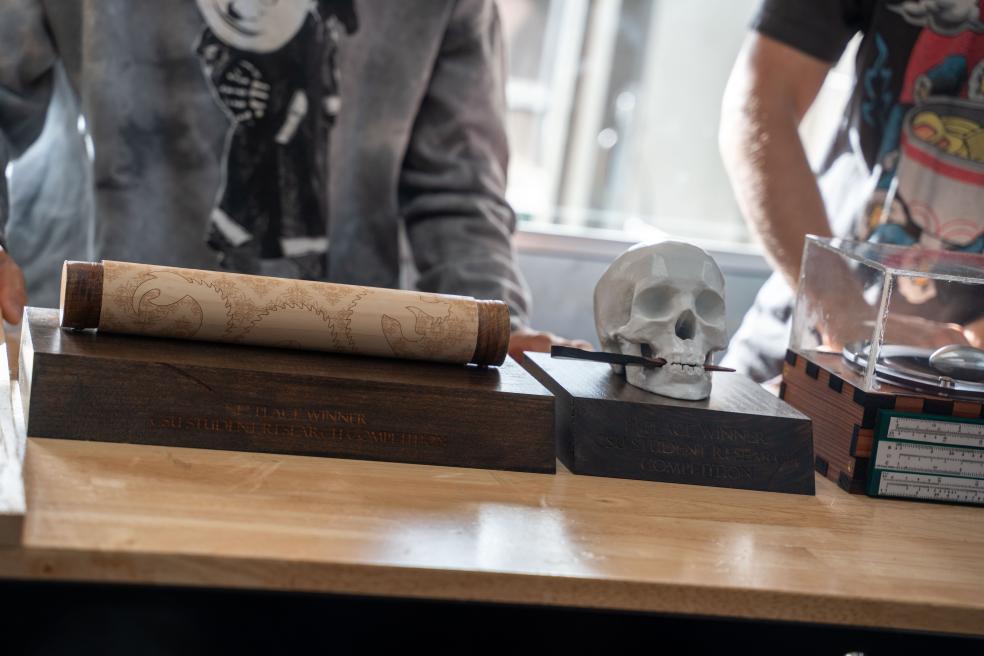 The trophies for the Humanities and Letters category winners include a skull with a letter opener, and scroll and scroll holder, calling back to ancient texts.