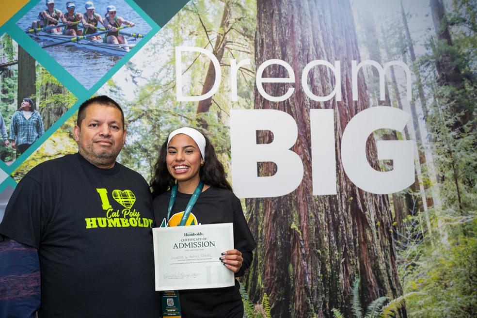 A photo of a student and parent holding a certificate of admissions to Cal Poly Humboldt during Fall Preview 2024. 