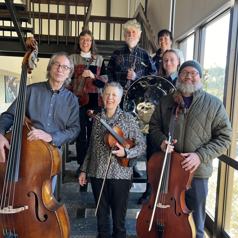 The concert's musicians standing on a staircase with their instruments in hand and smiking. 