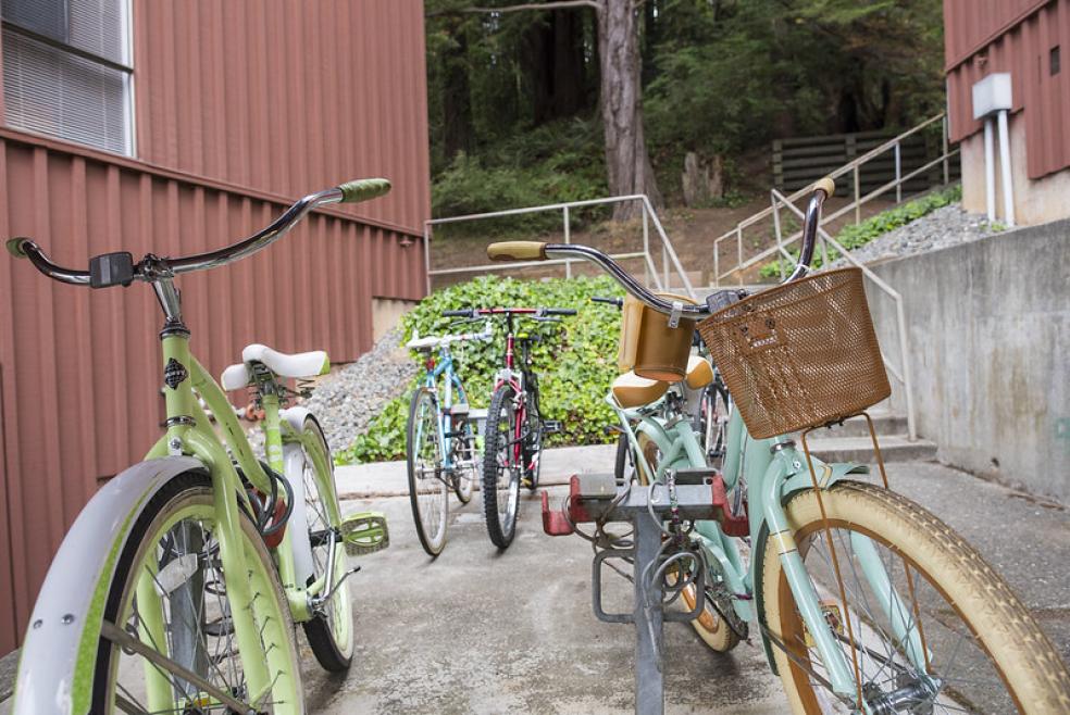 A photo of different colored bicycles parked near the Canyon student housing. 