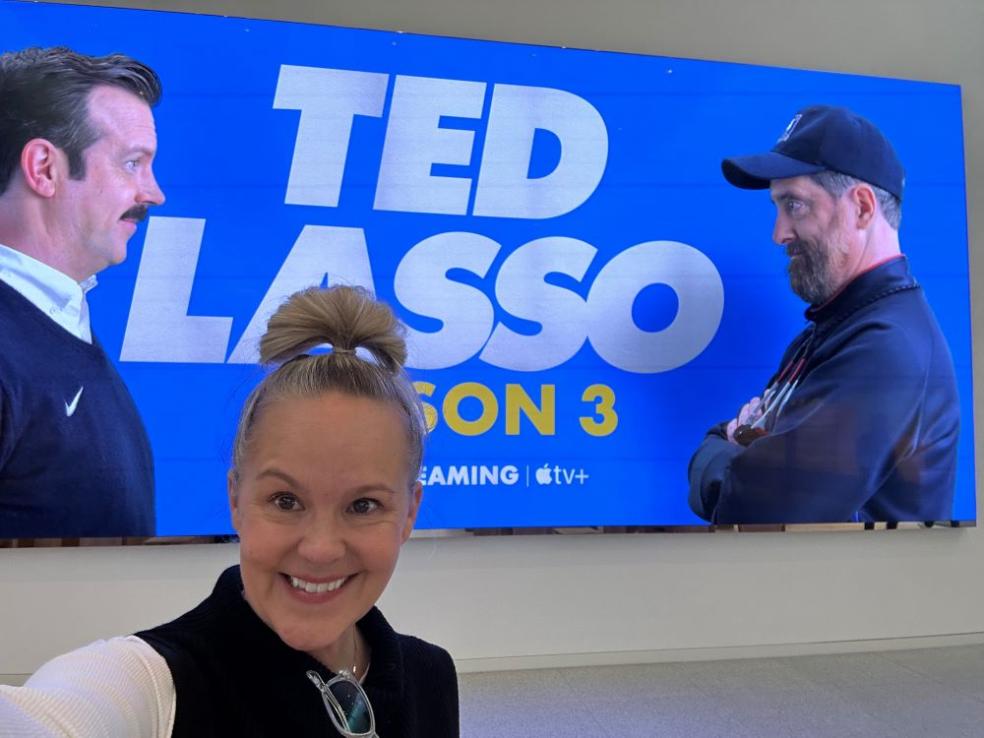 Leesa Coble A photo of Leesa Coble in front of a poster for Ted Lasso