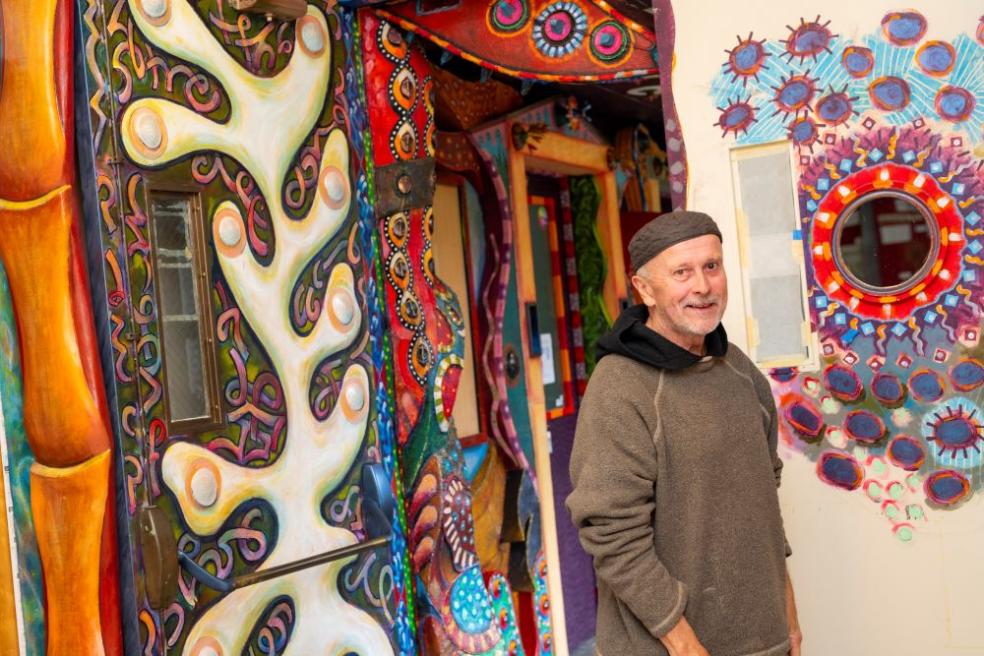 David White A photo of artist David White posing in front of the art hallway he created.