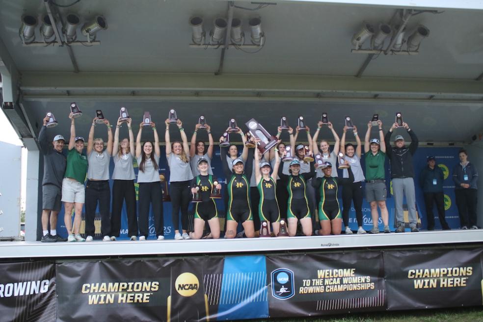 rowing team on stage holidng trophies