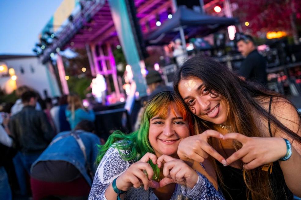 A photo of two students shaping their hands into the shape of hearts in front of the stage at Lumberjack Weekend 2024. 