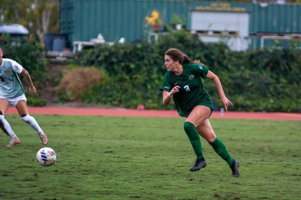 Women's Soccer player on the field running toward ball