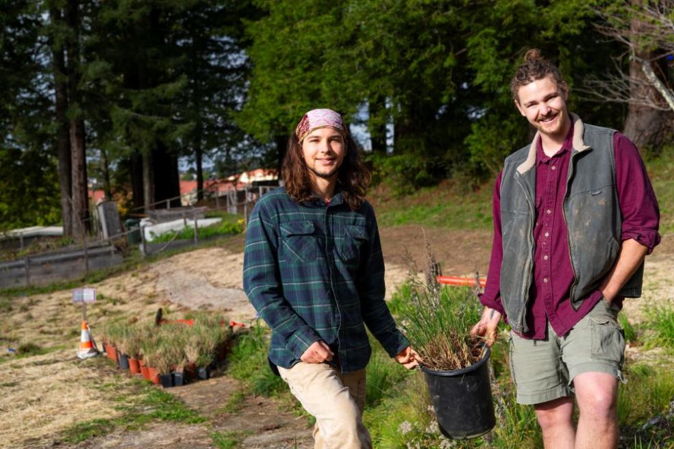 A photo of students Jack McCann and Carter Daniel holding a native plant ready to be planted in the pocket prairie sight. 