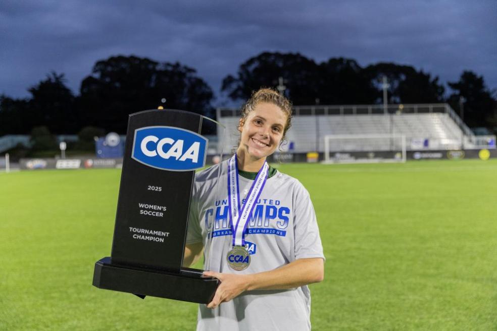 A photo of Cal Poly Humboldt women's soccer player Josie Wolitzky holding the CCAA Women's Tournament trophy. 