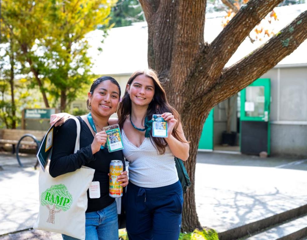 A photo of two students posing for a photo while holding up their Spring Preview name tags. 