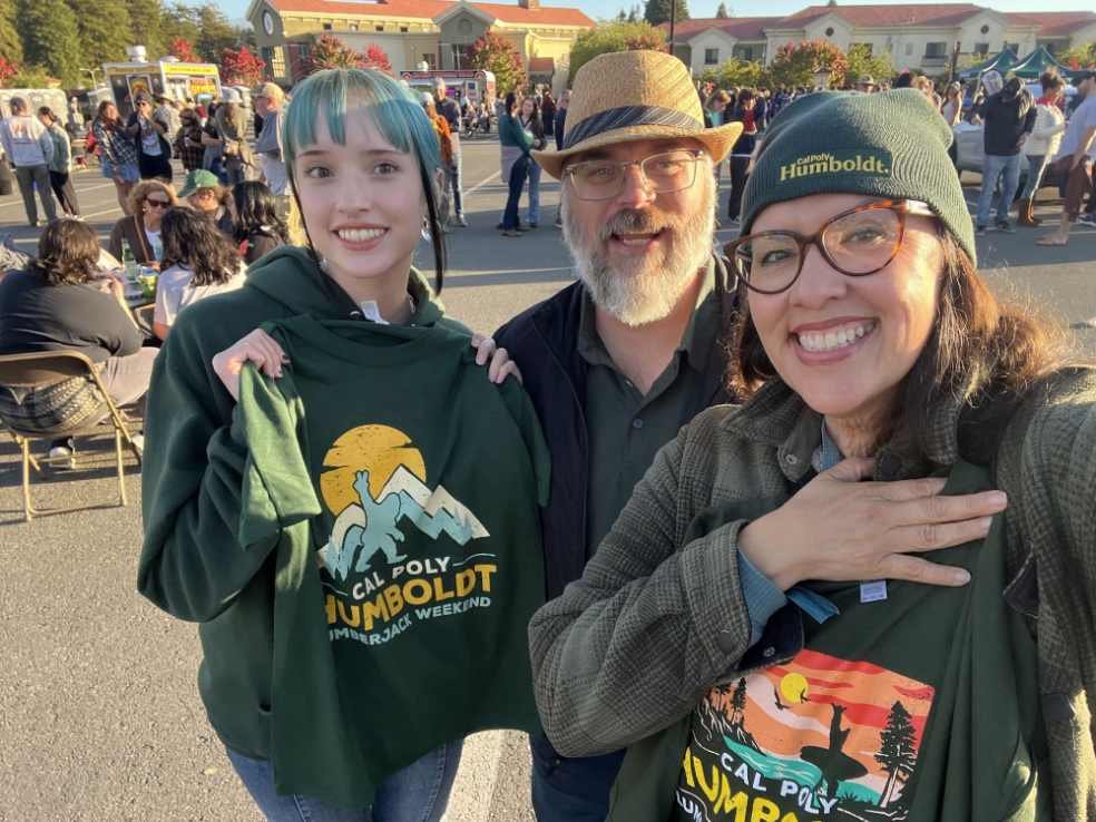 A photo of Cal Poly Humboldt Geology student Angelina Regan with her parents at Lumberjack Weekend