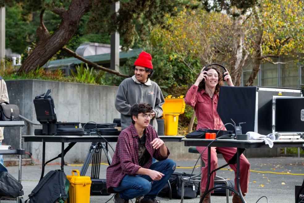 A photo of two students and Art + Film Professor Sarah Lasley working on a film project near the Van Duzer Theatre.