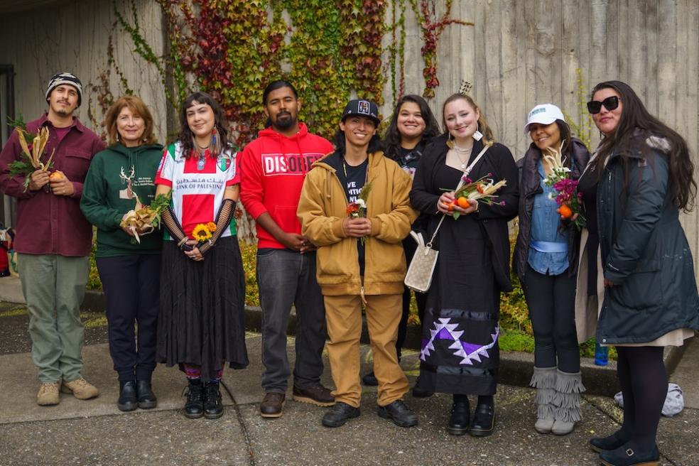A group of students and staff standing side by side and smiling at the camera. 