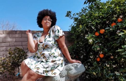 Sabina Gallier sitting next to a citrus tree wearing a dress. 