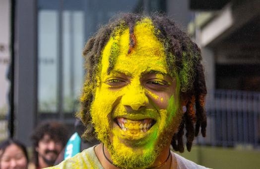 Alex Anderson's award-winning photo of Dakari Tate, a Cal Poly Humboldt Wildlife major whose face is covered in yellow powder for the Holi festival outside the Gutswurrak Student Activities Center on March 24, 2023.