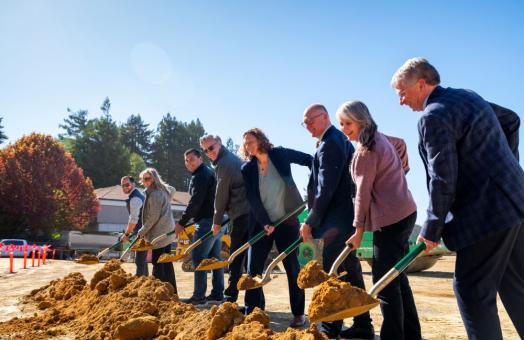 From left to right a photo of Jeff Good, Danielle Martin Spicer, Mike Fisher, Michael E. Spagna, Jenn Capps, Eric Riggs, Eileen Cashman, and Dale Oliver shoveling dirt on the construction site of the new Engineering & Technology Building, set to open Fall 2026.