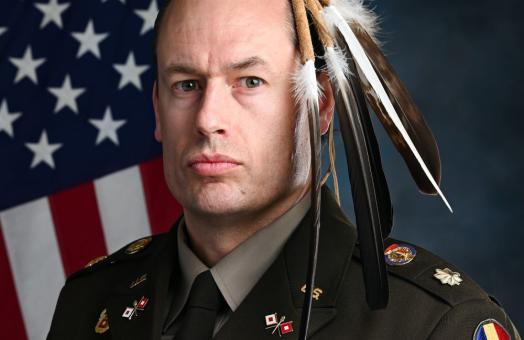 A portrait of Maj. Patrick Sorensen wearing his Native American regalia of feathers while wearing his U.S. Army uniform. 