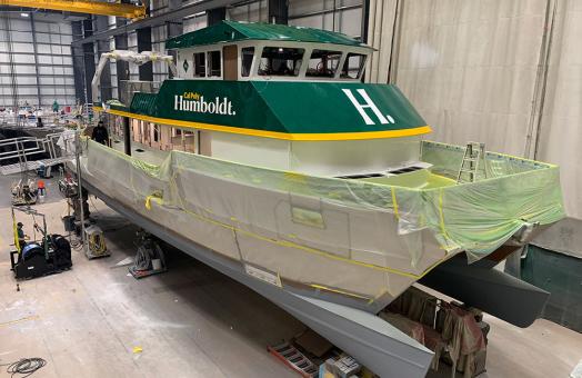 the R/V North Wind in a warehouse with plastic sheeting covering its lower half