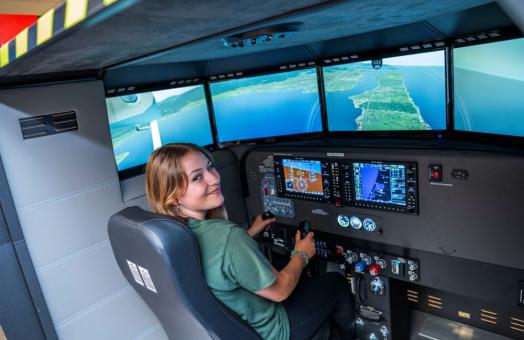 A photo of Humboldt student Harmony Switzer Tryon using the flight simulator at the Library. 