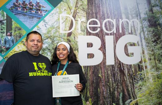 A photo of a student and parent holding a certificate of admissions to Cal Poly Humboldt during Fall Preview 2024. 