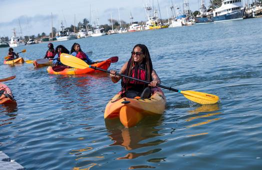 student in kayak paddling in Humboldt Bay as part of a Black to the Land event