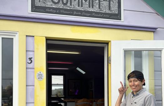 A photo of Michelle Cartier pointing at The Summitt sign at the entrance of The Summitt