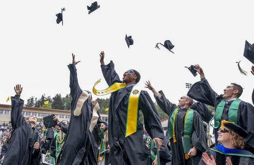 A photo of graduates throwing their caps during Spring Commencement in the Redwood Bowl. 