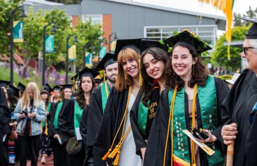 A photo of three graduates smiling at the camera during Spring Commencement 2025. 