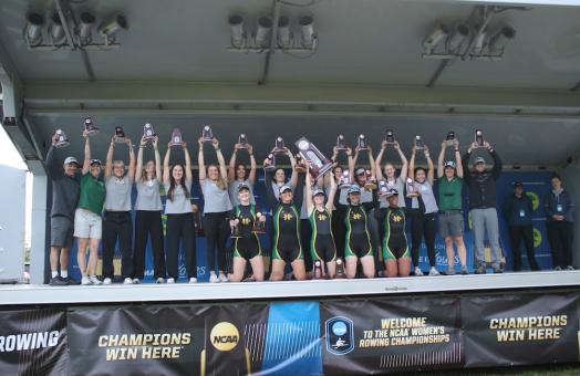 rowing team on stage holidng trophies
