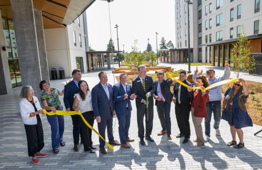 A photo (from left to right) of Alex Stillman, Kassidy Banducci, Mike Fisher, Damon Connolly, Chris Rogers, President Spagna (scissors), Mike McGuire, Eduardo Cruz, Chrissy Holliday, Cedrik von Briel, Donyet King cutting the ribbon at the Hinarr Hu Moulik student housing complex. 