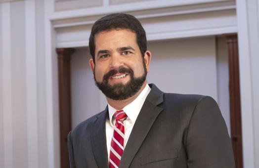 Dr Carvajal wearing a suit with a red and white striped tie smiling