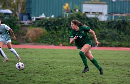 Women's Soccer player on the field running toward ball