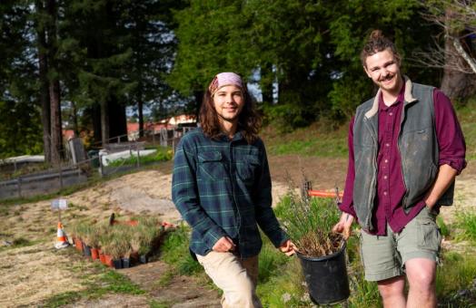 A photo of students Jack McCann and Carter Daniel holding a native plant ready to be planted in the pocket prairie sight. 