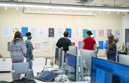 student reviewing posters of class projects on a wall