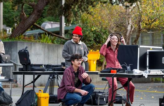 A photo of two students and Art + Film Professor Sarah Lasley working on a film project near the Van Duzer Theatre.