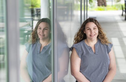 Connie leans against a building and smiles