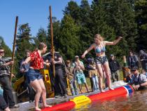 Two contestants battle it out while balancing on a floating makeshift log during the birling competition.