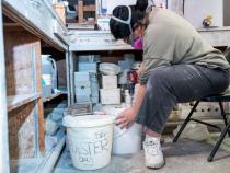 a photo of a student sitting down while mixing silicone together to create a mold.