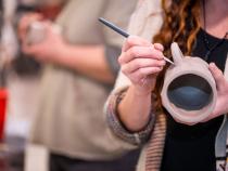 A photo of a student carving the clay mugs.