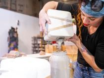 A photo of a student pouring silicone to create a mold for a ceramic mug.