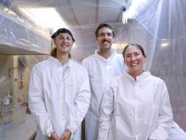 From left to right: Noah Schuhmann, Ralph Till, and Claire Till stand inside the “bubble,” a cleanroom they constructed onboard the research vessel to prevent potential contamination of the seawater samples they collected. Photo from Karina Vivanco.